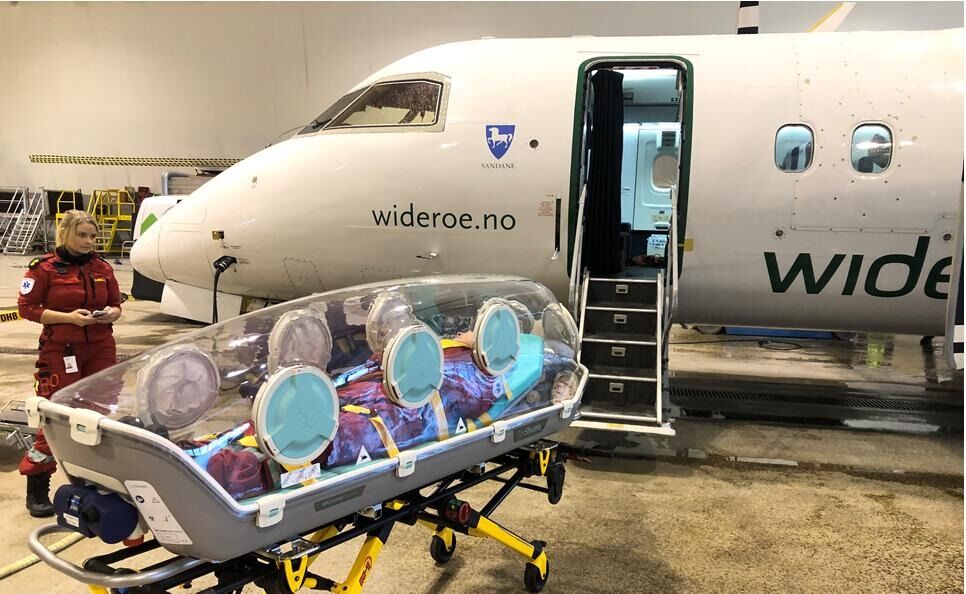 PLASS TIL TO. Widerøes Dash 8 - 100 og smittevernkuvøsen som kan brukes til å franke korona-pasienter i nord. Flyet har plass til to slike.
 Foto: Luftambulanseavdelingen, Universitetssykehuset Nord-Norge HF.