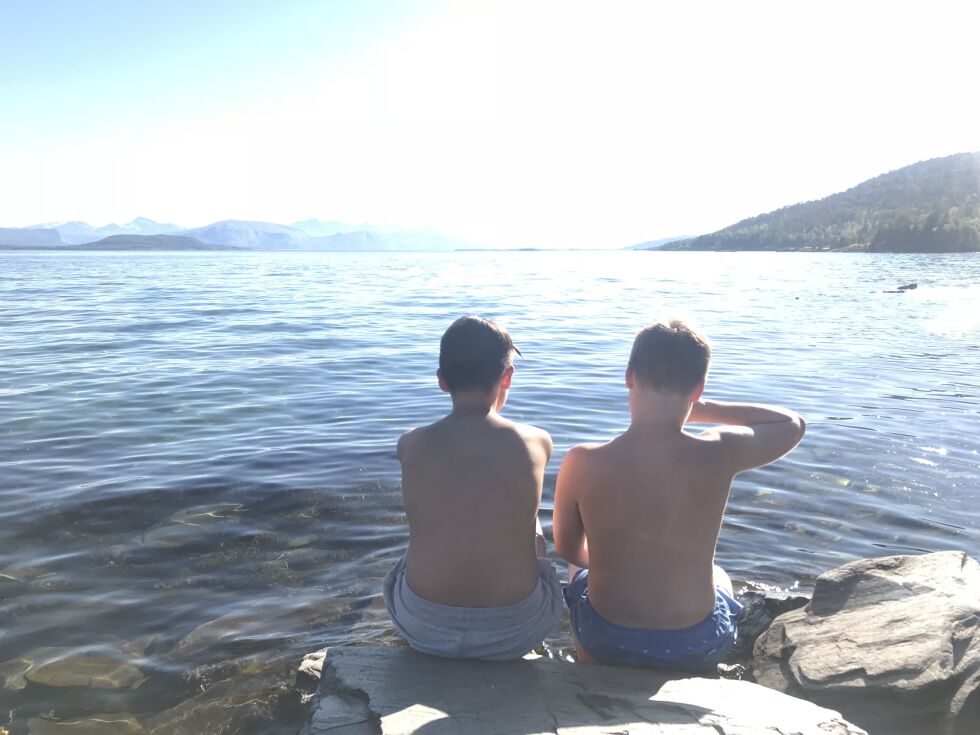 I FJÆRSTEINENE. To søskenbarn i Nordvika sitter i sola og venter på floa. Nå blir det nok mange badegjester på et av områdets mest populære badeplasser.
 Foto: Maria Trondsen