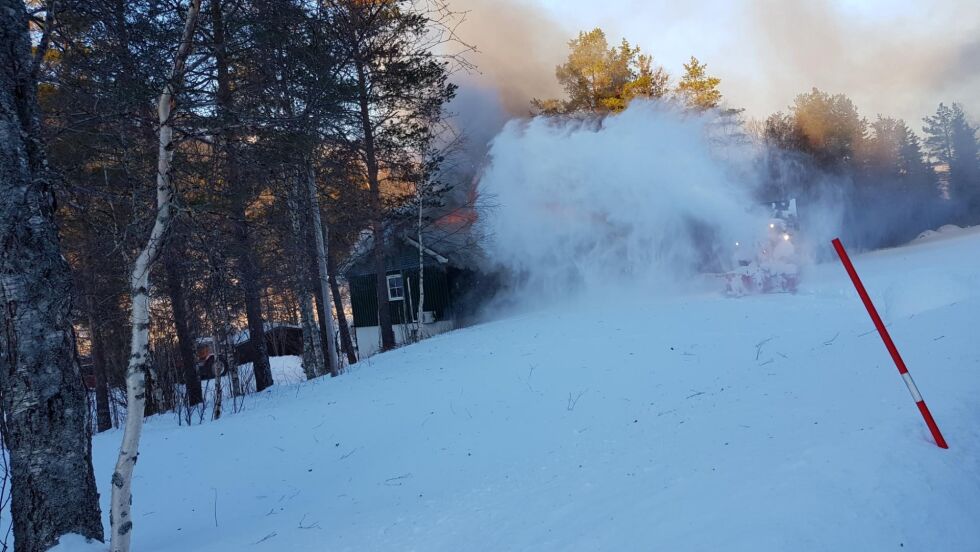 KASTER SNØ: En snøfres er på stedet og blåser snø ned mot huset som brenner.
 Foto: Bjørn Trones