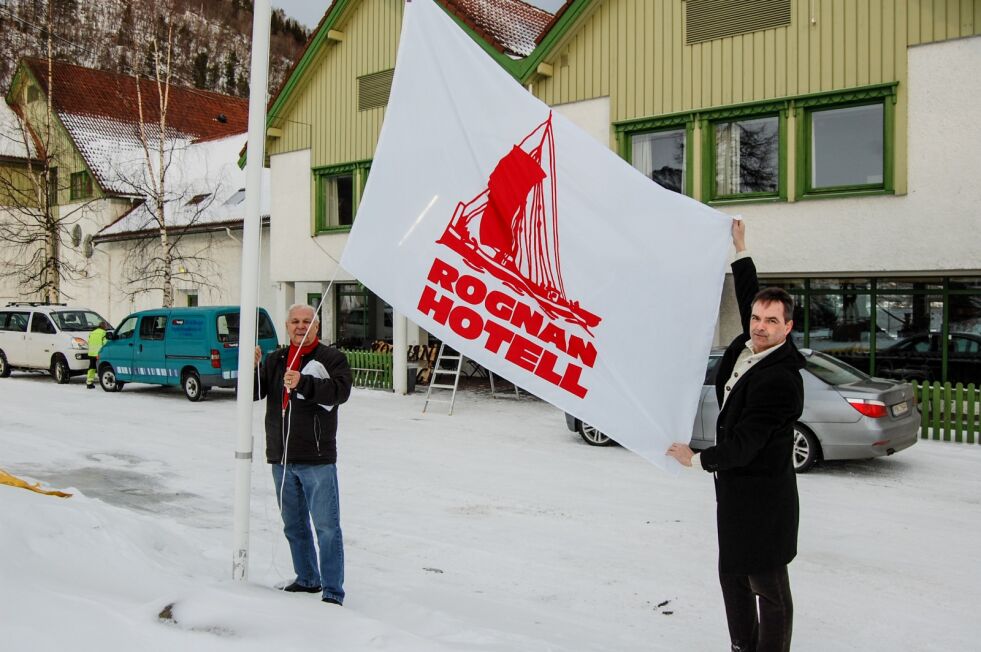 NYE EIERE. Harald Hartviksen og Roger Øksheim heiser flagget på Rognan hotell, for å markere at hotellet fikk nye eiere i starten av mars 2017. De nye eierne har sørget for økt aktivitet i hotellet, men ifølge revisorberetningen har de ikke avlagt et årsregnskap som kan godkjennes for 2018.
 Foto: Sven Thoresen
